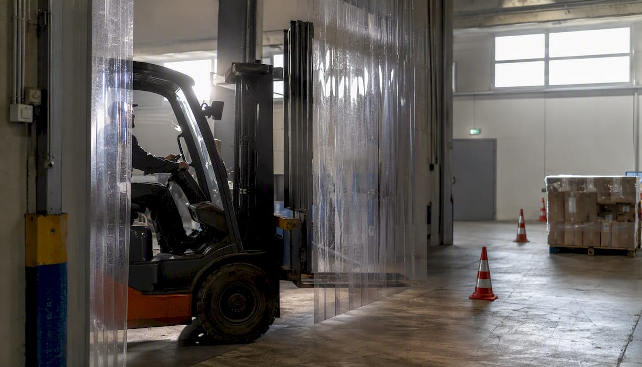 Kurtyna paskowa z PCV, przez którą przejeżdża wózek widłowy